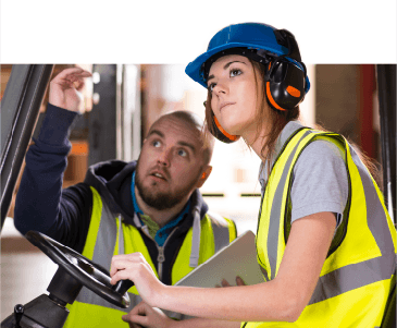 Man teaching woman operating machinery
